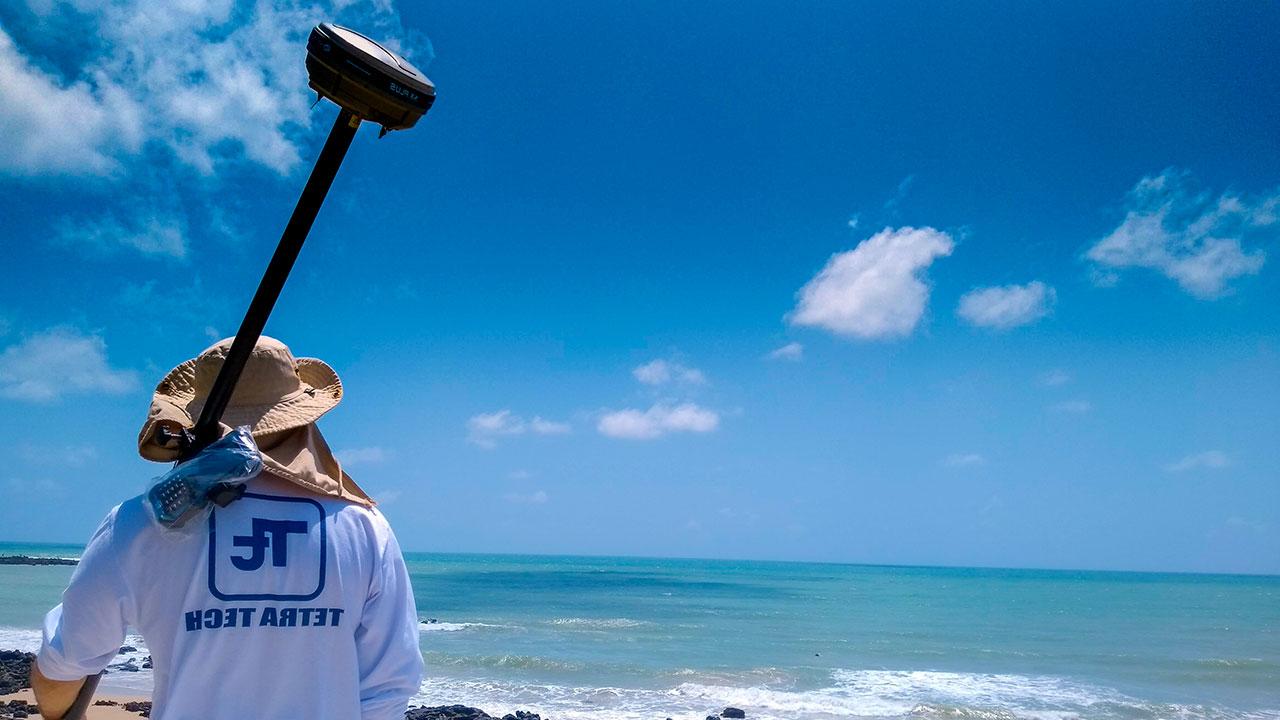 A Tetra Tech employee standing at Ponta Negra Beach holding equipment